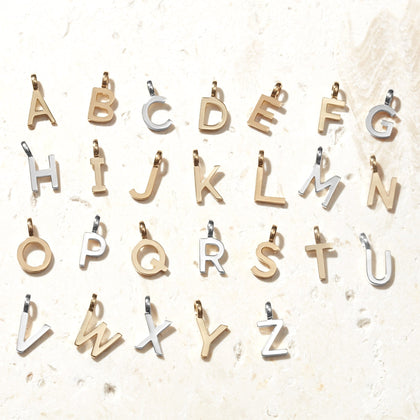 a mixture of silver and gold letter charms laid out in alphabetical order on a white background